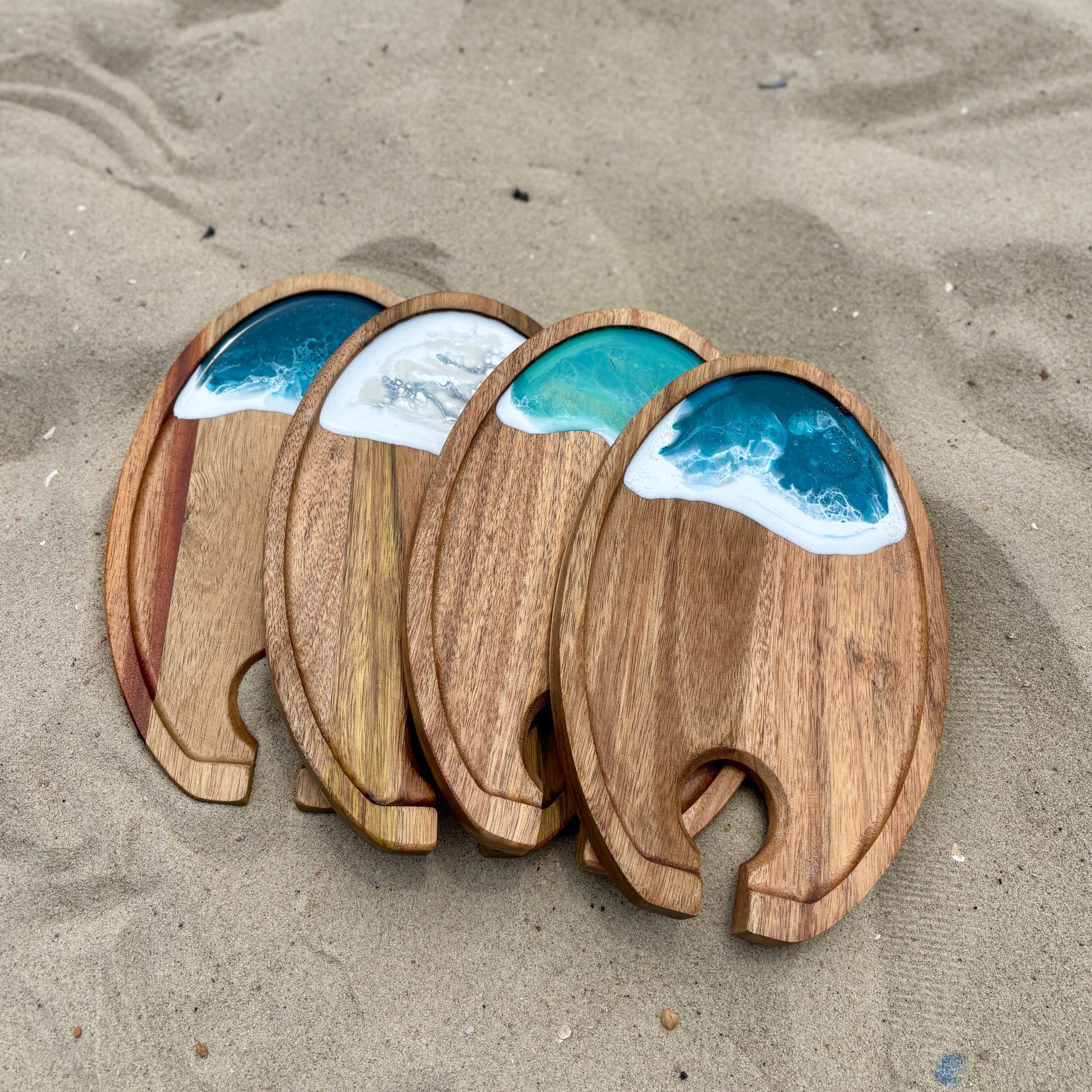 Wooden coasters with ocean wave design on a sandy surface