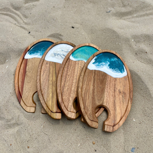Wooden coasters with ocean wave design on a sandy surface